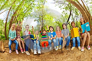 Happy kids reading books outdoor in summer camp