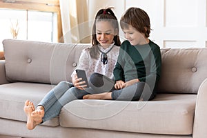 Happy kids relax on sofa at home with cellphone