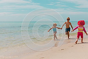 Happy kids run on beach, boy and girl play with water