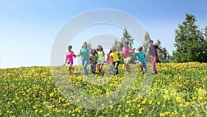 Happy kids run together in dandelion field