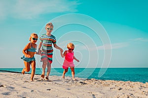 Happy kids running on beach, boy and girls have fun at sea