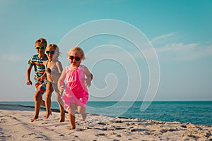 Happy kids running on beach, boy and girls have fun at sea