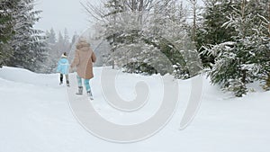 Happy kids running on snowy spruce forest.