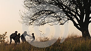 Happy kids rushes into hands of parents. Parents hugs their kids in the meadow.