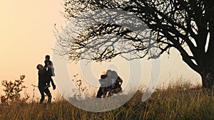 Happy kids rushes into hands of parents. Parents hugs their kids in the meadow.