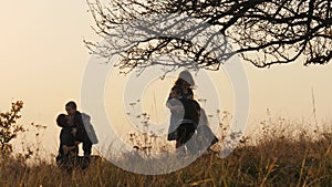 Happy kids rushes into hands of parents. Parents hugs their kids in the meadow.