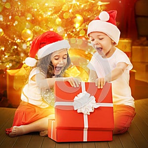 Happy kids in Santa hat opening a gift box