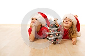 Happy kids with santa hats laying on the floor