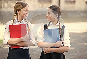 Happy kids in school uniform hold study books outdoors, library