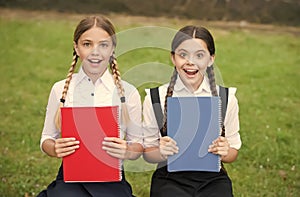 Happy kids in school uniforms show colorful schoolbooks covers outdoors, books
