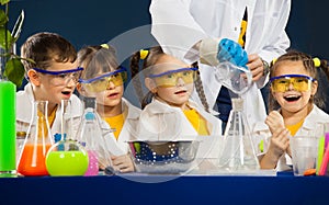 Happy kids with scientist doing science experiments in the laboratory