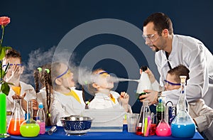 Happy kids with scientist doing science experiments in the laboratory