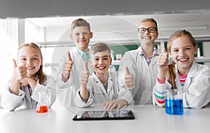 Happy kids showing thumbs up at school laboratory