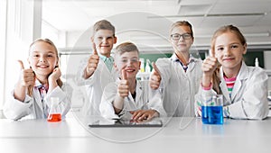 Happy kids showing thumbs up at school laboratory