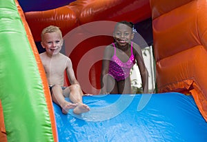 Happy kids sliding down an inflatable bounce house