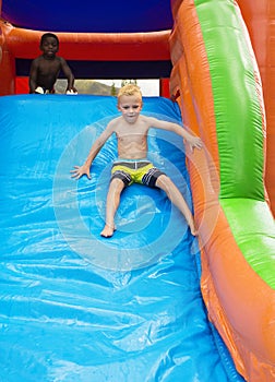 Happy kids sliding down an inflatable bounce house