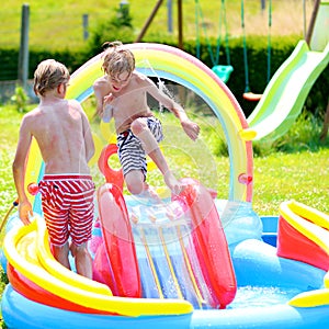 Happy kids splashing in inflatable garden pool