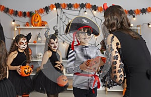 Happy kids in spooky costumes go trick or treating and get candy at Halloween parties