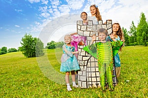 Happy kids in theatric costumes play around tower