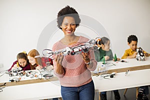 Happy kids with their African American female science teacher  programming electric toys and robots at robotics classroom