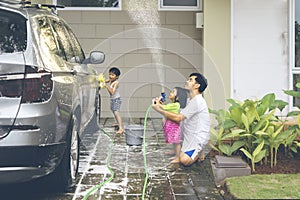 Happy kids and their father washing a car