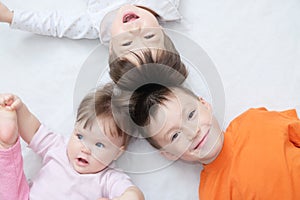 Happy kids, three laughing children different ages lying, portrait of boy, little girl and baby girl, happiness in childhood