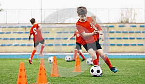 Happy Kids on Training Soccer Drill. Football Summer Camp. Young European Footballers Dribbling Around Cones