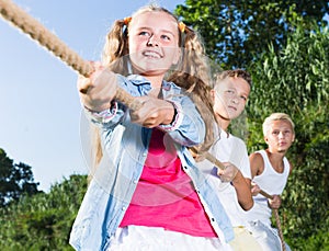 Happy kids tugging war in summer park