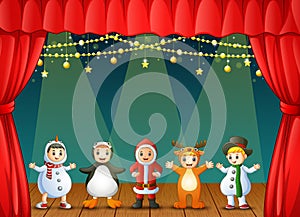 Happy kids wearing christmas costumes performing on stage