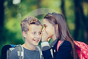 Happy kids whispering a secret each other in the ears