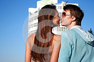 Happy kissing couple near new white building