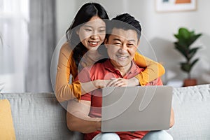 Happy korean couple using computer together at home