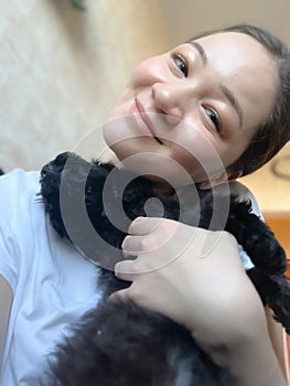 Happy Korean girl holding a black toy poodle puppy. Get a pet. Asian woman with puppy. Happiness. Smiling female person