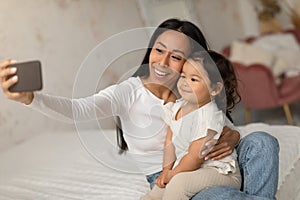 Happy Korean Mom Making Selfie With Baby Daughter At Home