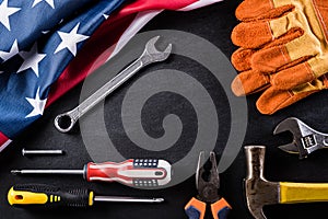 Happy Labor day concept. American flag with different construction tools on black table background, with copy space for text