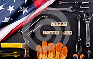 Happy Labor day concept. American flag with different construction tools on black table background, with copy space for text