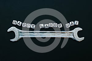 Happy labor day concept greeting card background. Wrench with word happy labour day on blackboard background.