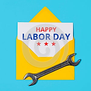 Happy labor day concept. Yellow Envelope and wrench on blue background.