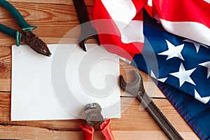 Happy Labor day. Construction tools, white mockup blank and American flag on wood background.