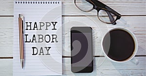Happy labor day text over diary against coffee cup, glasses and smartphone on wooden background