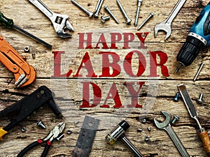 Happy Labor day text in red color on wooden background with construction repair tools. photo