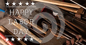 Happy labor day text and stars against multiple tools on wooden background