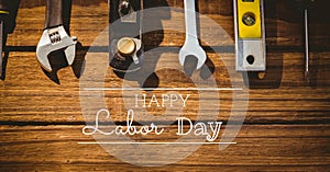 Happy labor day text and stars against multiple tools on wooden background