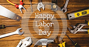 Happy labor day text and stars against multiple tools on wooden background