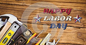 Happy labor day text and stars against multiple tools on wooden background