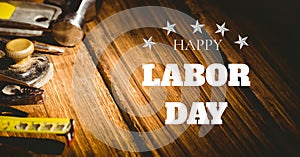 Happy labor day text and stars against multiple tools on wooden background