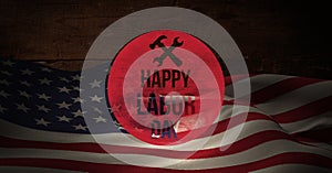 Happy labor day text and tool icon against american flag on wooden background