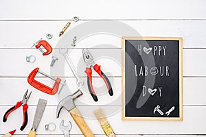 Happy Labour Day background concept. Flat lay of construction handy tools with black chalkboard with happy labour day text over