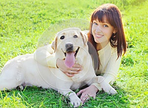 Happy labrador retriever dog and owner woman lying on the grass