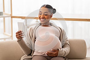 happy lady expecting baby watching funny videos and smiling